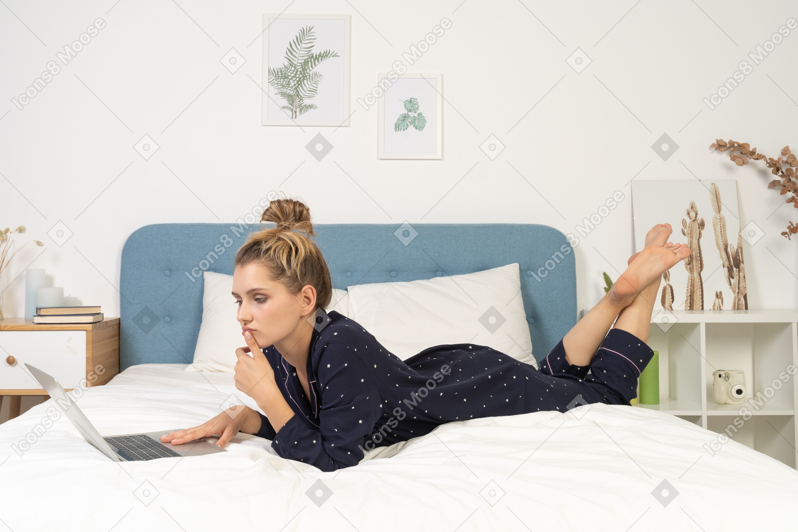 Side view of a young female laying in bed with her laptop