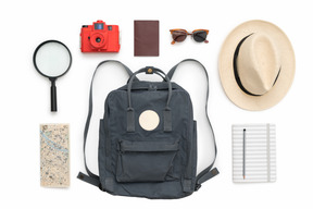 Dark blue backpack, straw hat, magnifying glass and other travelling items