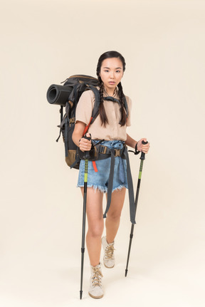 Joven excursionista mujer caminando con bastones de trekking