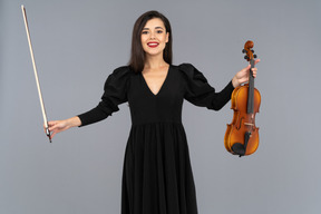 Front view of a female violin player in black dress making a bow