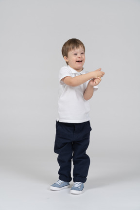 Улыбающийся маленький мальчик стоит с поднятыми руками