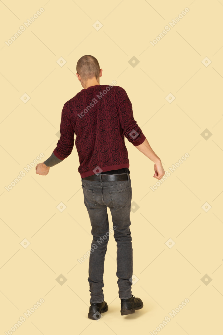 Vista posteriore di un giovane uomo che balla vestito con un pullover rosso