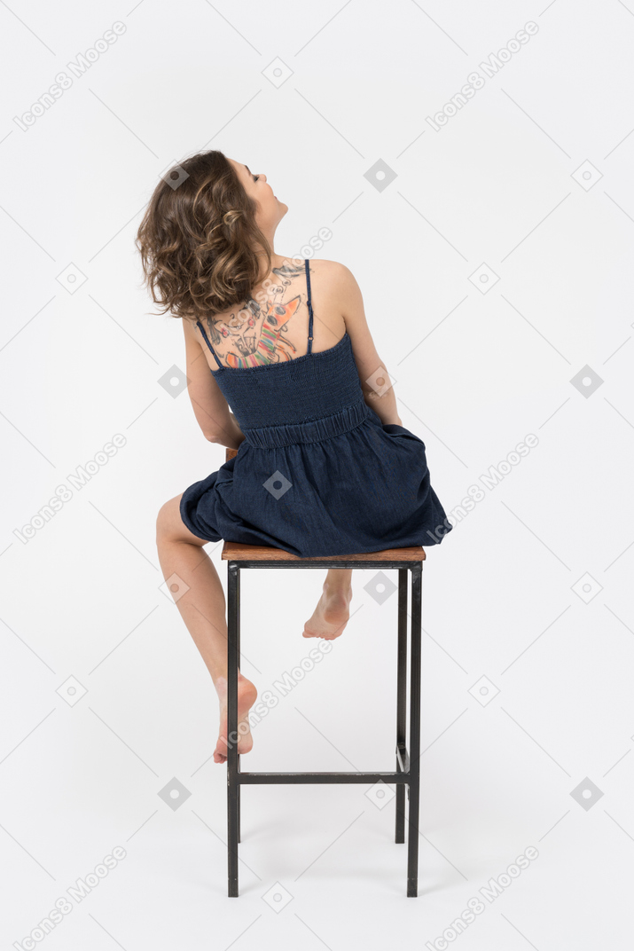 Woman with tattooed back sitting on a bar stool