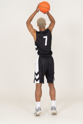 Vista traseira de um jovem jogador de basquete jogando uma bola