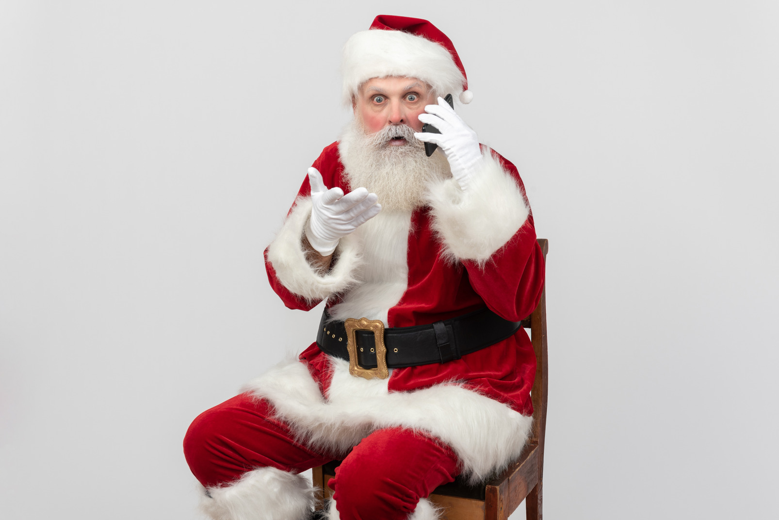 Surprised santa claus sitting and talking on the phone