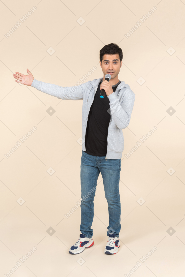 Молодой кавказский человек говорит в микрофон