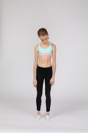 Front view of a teen girl in sportswear bending her head down