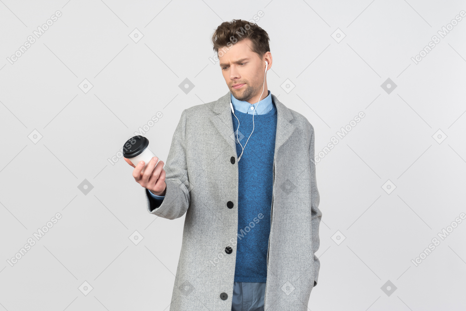 Handsome young guy listening to music and looking on cup of coffee