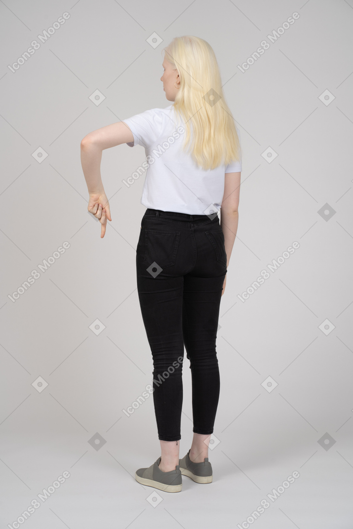 Back view of a young blonde girl standing and pointing down