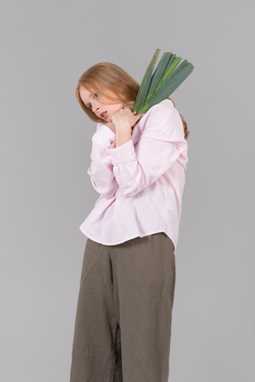 Young woman holding leek onion close to herself