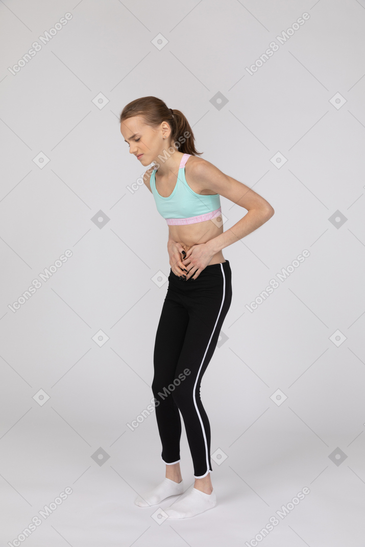 Menina adolescente em roupas esportivas com dor de estômago