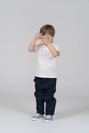 Vorderansicht eines kleinen jungen, der sein gesicht bedeckt
