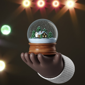 A hand holding a snow globe with a house in it