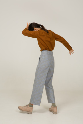 Back view of a flexing young asian female in breeches and blouse