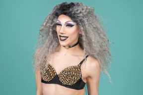 Drag queen in studded bra smiling happily