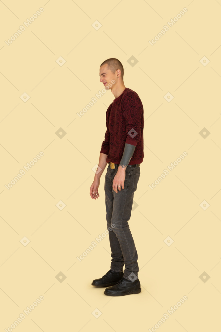 身振りで示す赤いセーターで若い顔をゆがめた男の側面図