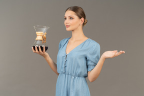 Three-quarter view of a young woman in blue dress holding a pitcher of wine