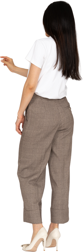 Vista posteriore di tre quarti di una giovane donna in calzoni e maglietta bianca che mostra una taglia di qualcosa