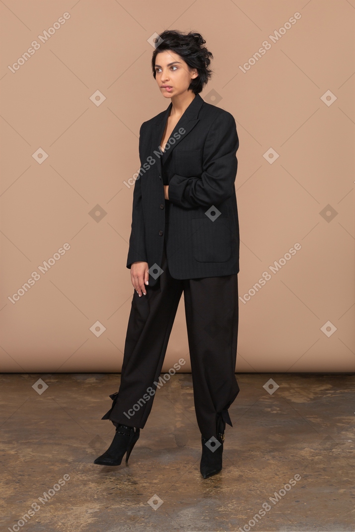 Three-quarter view of a thoughtful businesswoman stepping aside and biting lips
