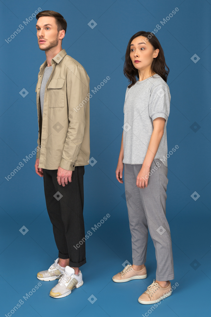 Young man and woman looking sideways surprisingly
