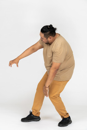 Plus size asian man stooping down with outstretched hand