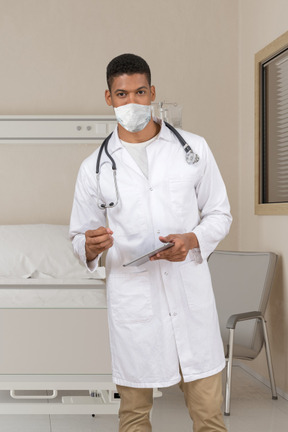 A male doctor in a white lab coat holding a clipboard