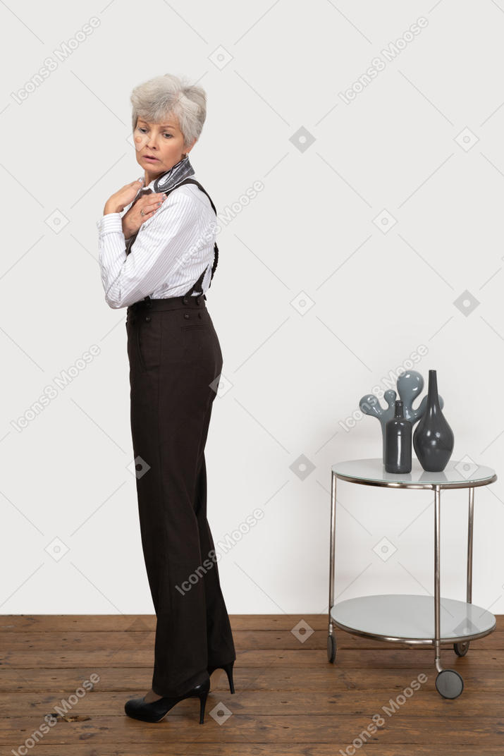 Side view of an old lady in office clothing embracing herself