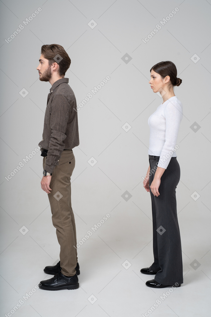 一对年轻夫妇在办公服装站着不动的侧视图