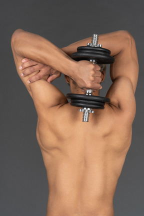 Back view of a shirtless afro man lifting the dumbbell