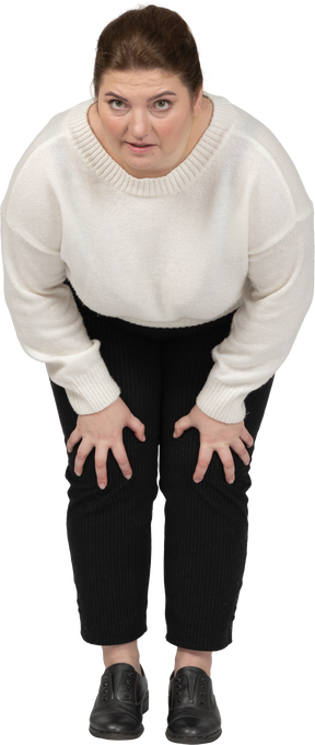 Пухлая женщина в повседневной одежде трогает колени