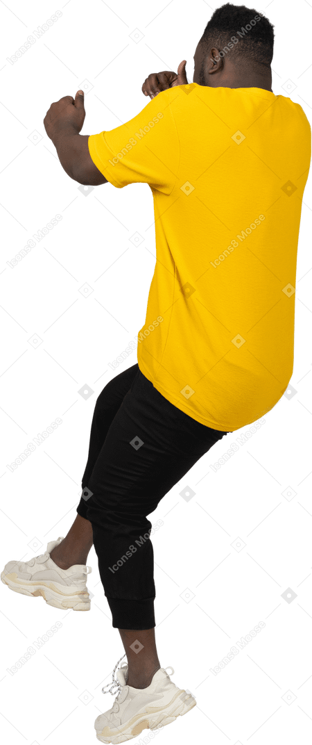 Vista posteriore di un giovane uomo dalla pelle scura in maglietta gialla che salta indietro