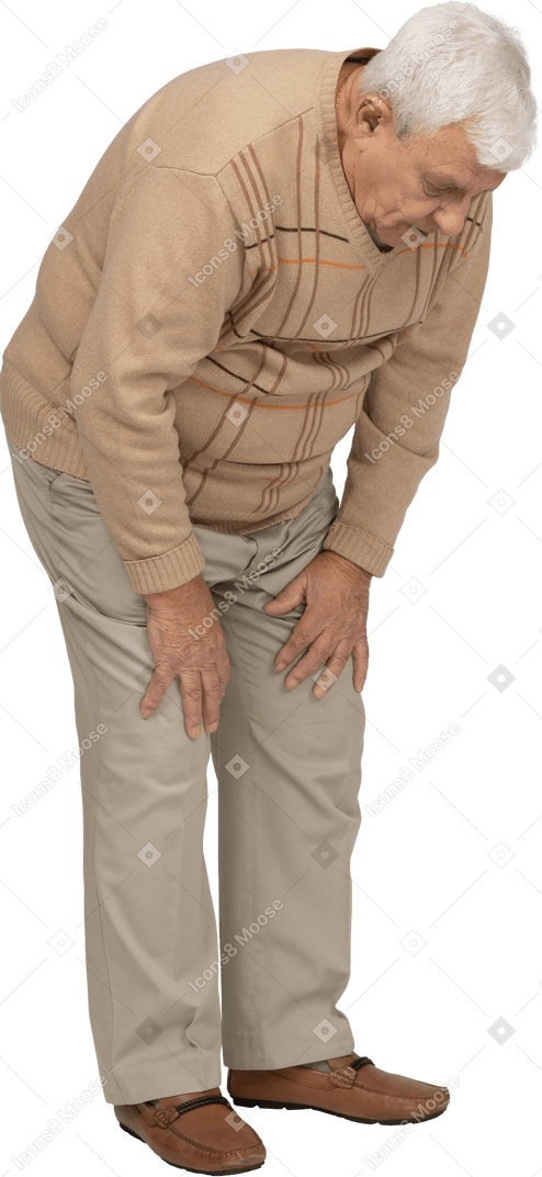 Vista lateral de um velho em roupas casuais, curvando-se e tocando seu joelho dolorido