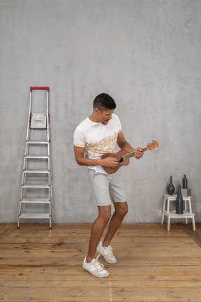 Three-quarter view of a man playing on ukulele