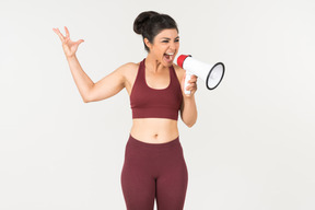 Angry looking young indian woman screaming using megaphone