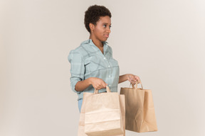 Unsatisfied young afro woman holding paper bags