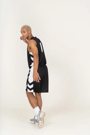 Vista posterior de tres cuartos de un joven jugador de baloncesto masculino alejándose