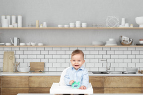 A baby sitting in a high chair in a kitchen