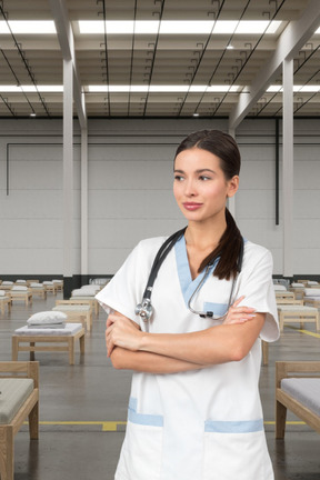 A nurse standing in a hospital room with her arms crossed