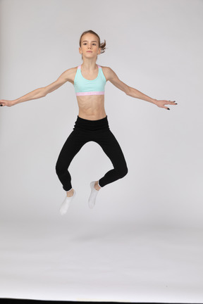 Side view of a teen girl in sportswear squatting and putting hands on hips