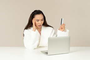 Bothered young asian woman doing online shopping