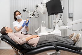 Comprimento total de uma dentista mostrando protótipo de dentes para paciente em um gabinete de hospital