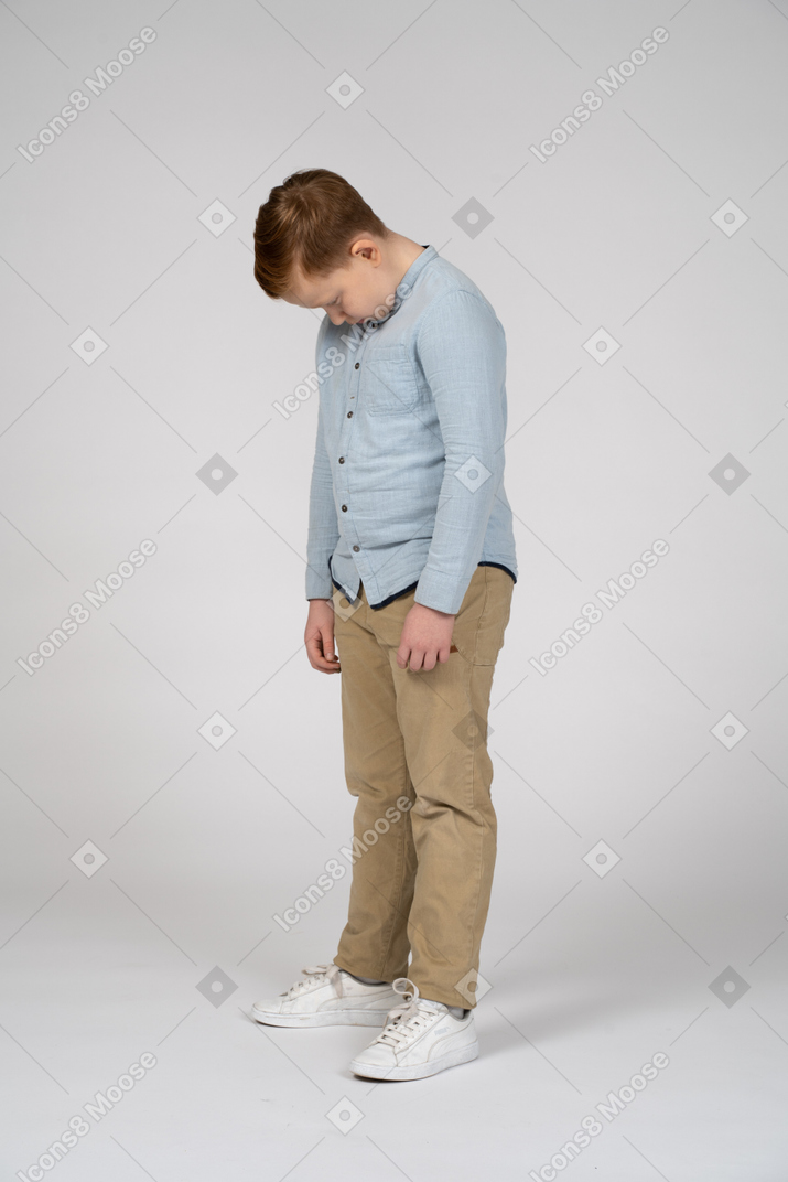 Cute boy standing with head bent down