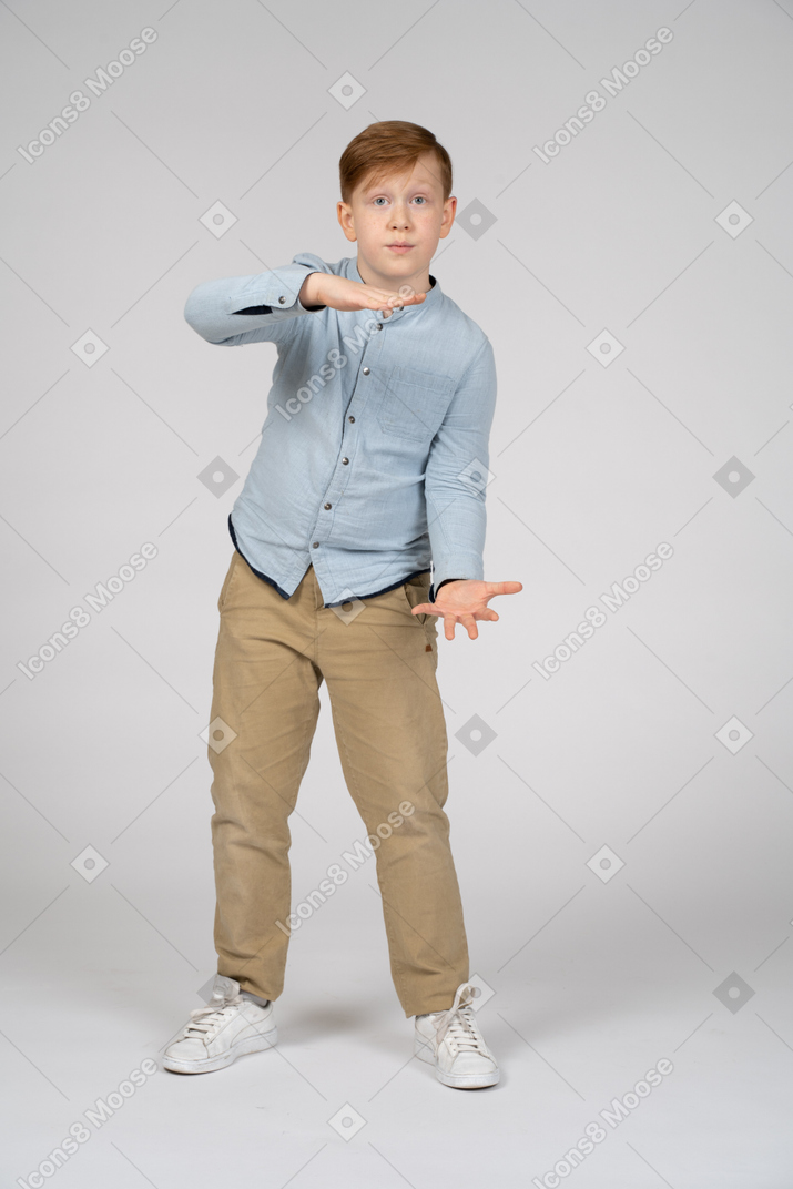 Front view of a cute boy showing size of something and looking at camera