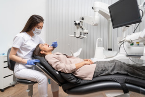 Full-length of a female dentist examining her patient with a mirror