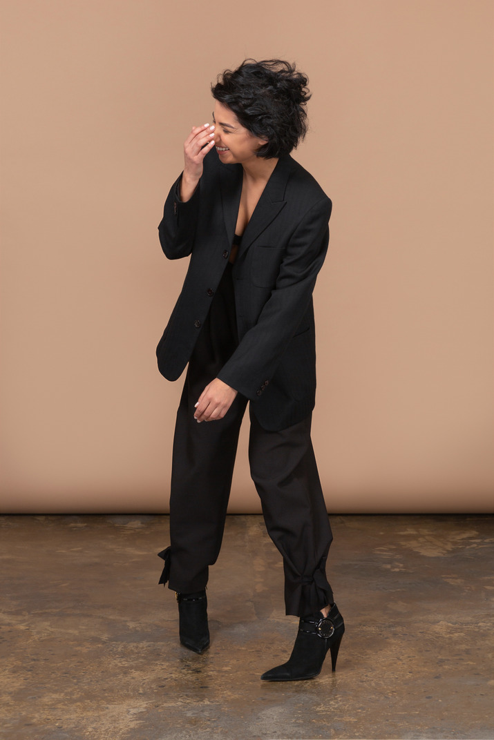 Front view of a laughing businesswoman wearing black suit and touching her nose