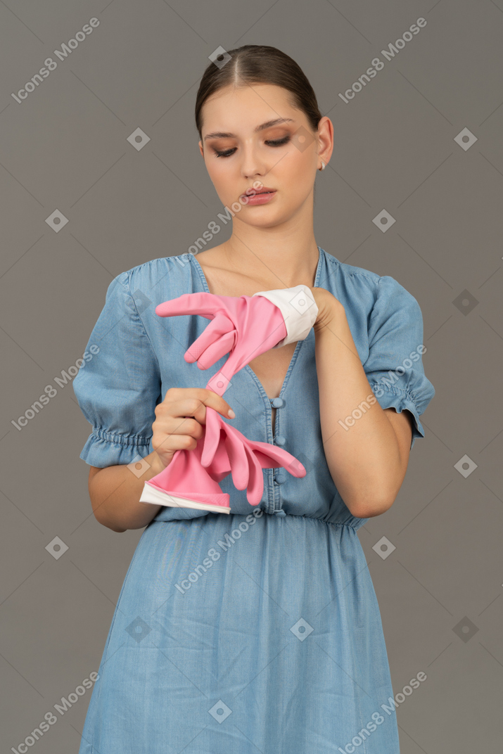 Portrait of a young woman taking off cleaning gloves