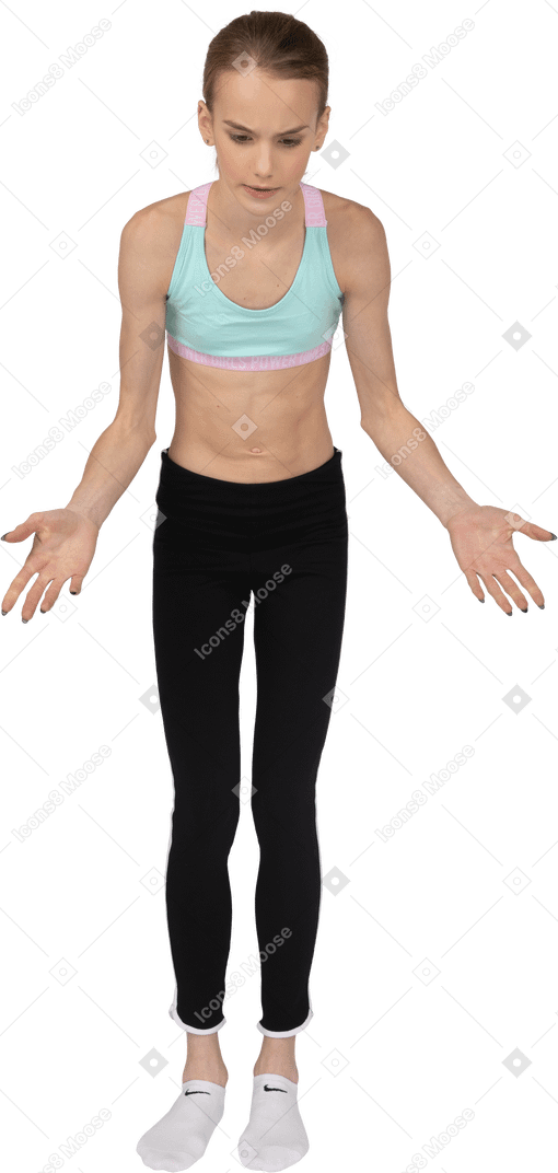 Vista frontal de uma adolescente em roupas esportivas estendendo as mãos e olhando para baixo