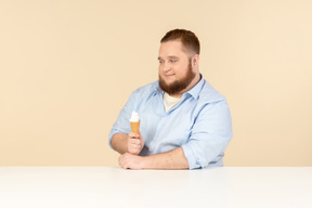 Gran hombre sentado a la mesa y con helado