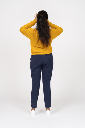 Rear view of a girl in casual clothes looking through fingers