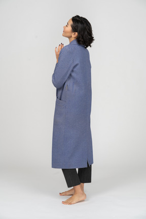 Vista lateral de uma mulher em pé de casaco